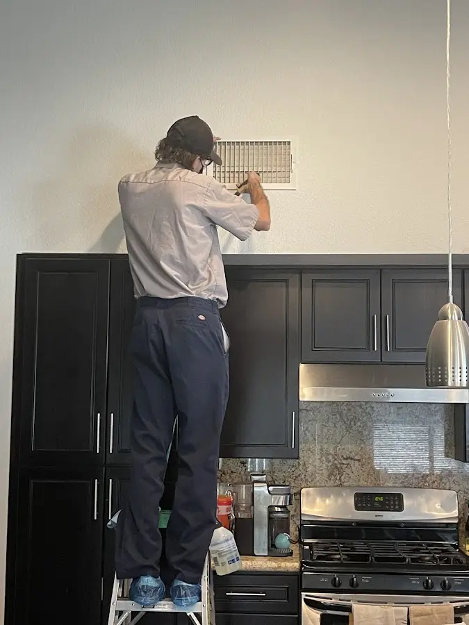 Technician inspecting an air vent during HVAC service in Orange